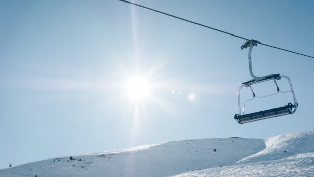 A ski lift against a clear blue sky over a snowy mountain slope