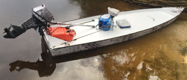 White skiff with motor and fishing gear on calm water surface