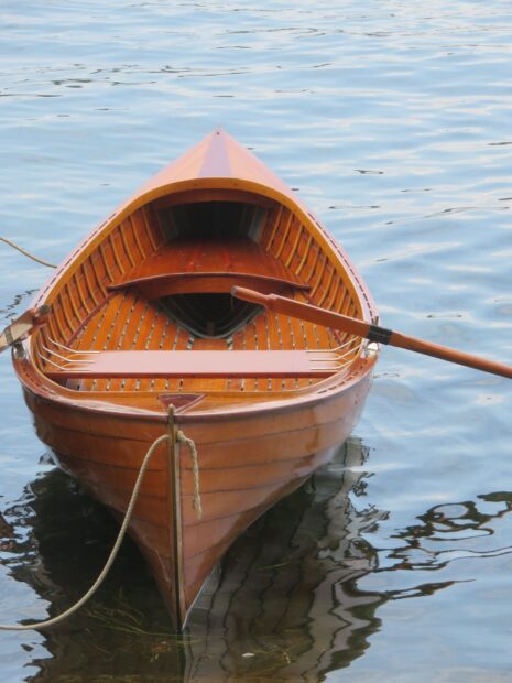 Wooden skiff floating on calm water with oars resting inside the boat