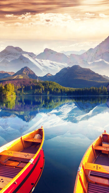 Two wooden skiff on a calm lake with snowy mountains reflecting on the water