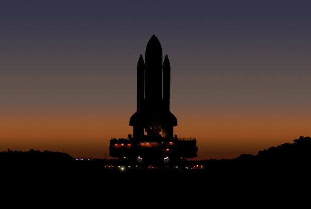 Space shuttle silhouette during sunset over the launch pad with clear sky