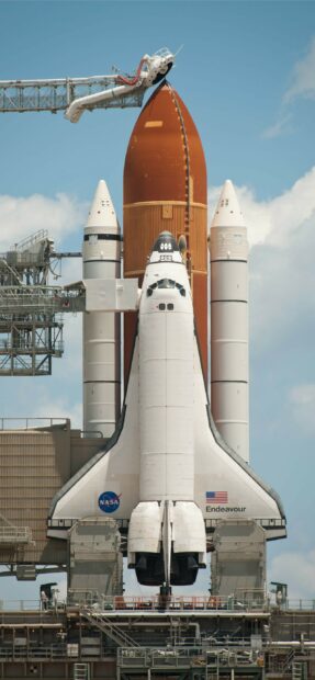Space shuttle Endeavour standing upright on launch pad with external fuel tank and solid rocket boosters