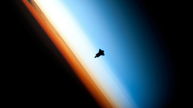Space shuttle silhouetted against the Earth's atmosphere showing space shuttle details