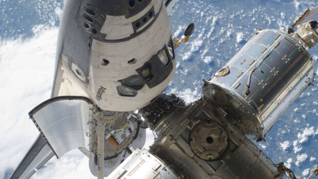 Space shuttle Atlantis docked with space station modules orbiting Earth viewed from space