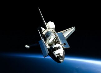 A space shuttle orbiting above the Earth in outer space with open payload bay doors