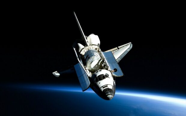 A space shuttle orbiting above the Earth in outer space with open payload bay doors