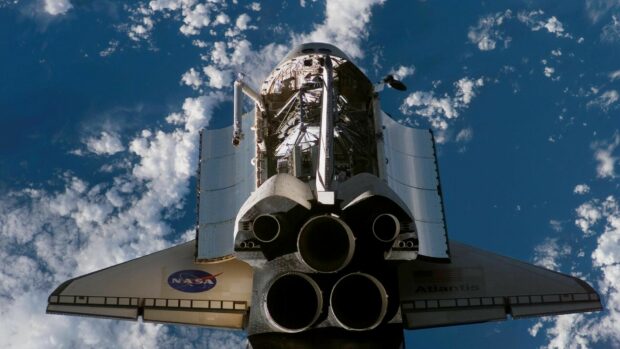 Space shuttle seen from behind with open cargo bay in orbit above Earth