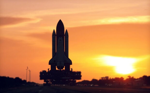 Space shuttle standing on the launch pad during a stunning sunset sky