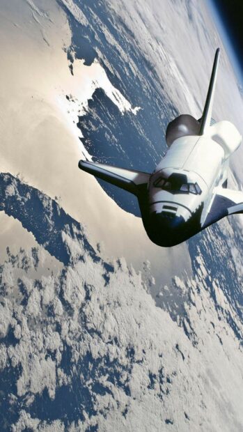 Space shuttle flying above Earth with clouds visible below in space
