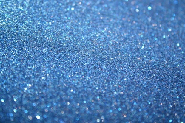 Close up of blue sparkle texture with shimmering glitter particles