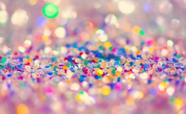 Colorful sparkle particles shining brightly with vibrant hues on a soft surface