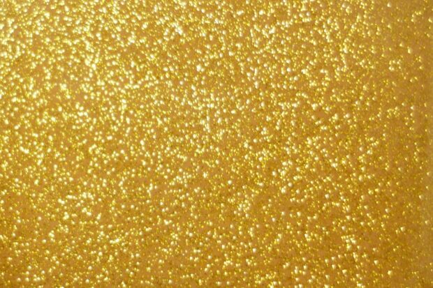 Golden sparkle texture with shiny glitter particles sparkling brightly on surface