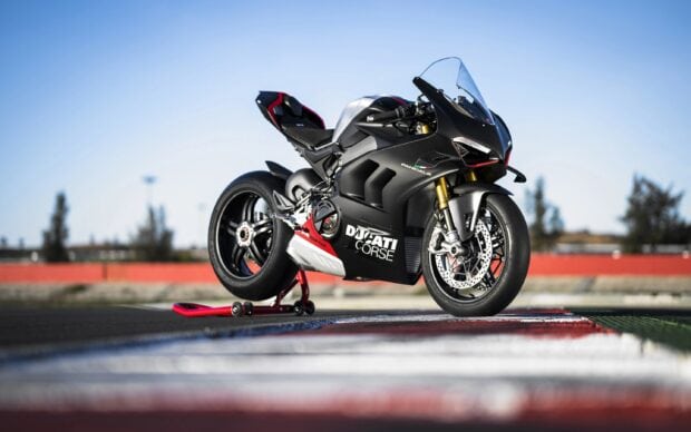 A Ducati sports bike parked on a racetrack with a clear sky background