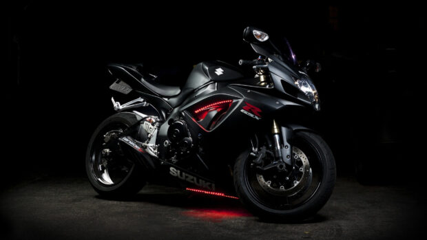 A black Suzuki sports bike with red accents parked on a dark surface in low light conditions