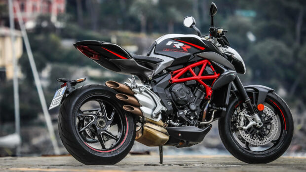A black and red sports bike parked on a concrete surface with a blurred natural background