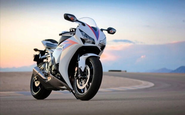 White sports bike parked on a road during sunset with mountains in the background