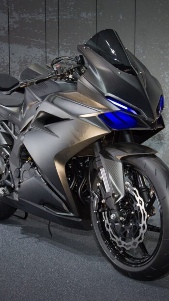 A sleek sports bike with blue headlights parked on a textured floor