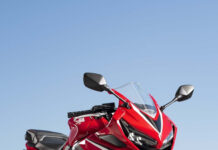Red sports bike parked on track reflecting on wet surface