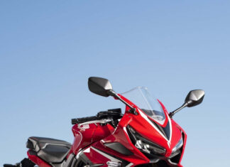 Red sports bike parked on track reflecting on wet surface