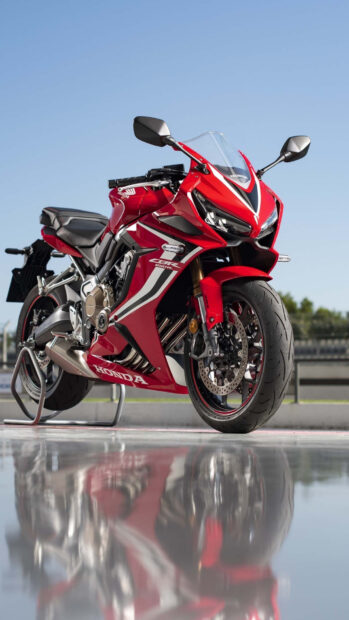 Red sports bike parked on track reflecting on wet surface