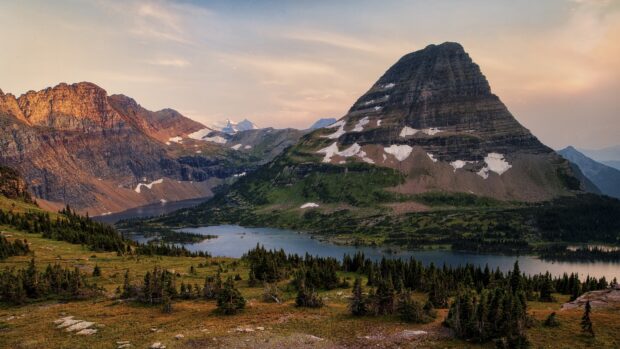 A scenic view of spruce trees by a mountain lake at sunset