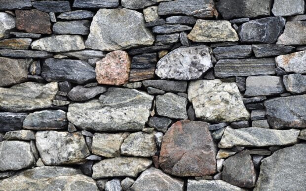 Close up of natural stone wall texture with various shapes and colors of stone bricks