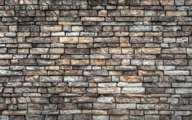 A detailed stone wall with various rectangular shapes and natural colors creating a rustic texture