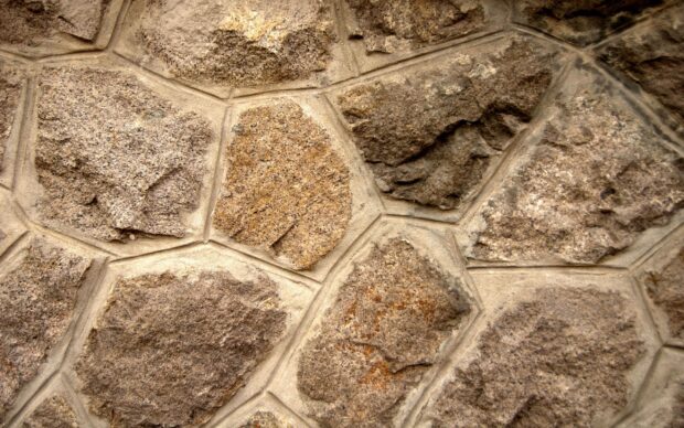 Close up of textured stone wall with irregular shapes and rough surface