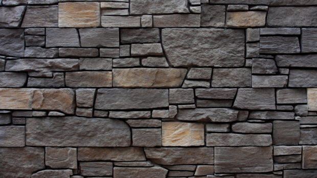 A close up view of stone wall showcasing natural rough texture and varied shapes of stone blocks
