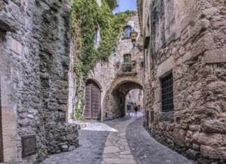 Narrow stone wall alley with old textured stone walls and cobblestone path