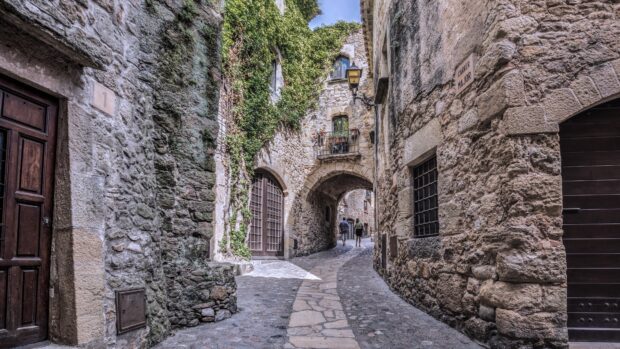 Narrow stone wall alley with old textured stone walls and cobblestone path