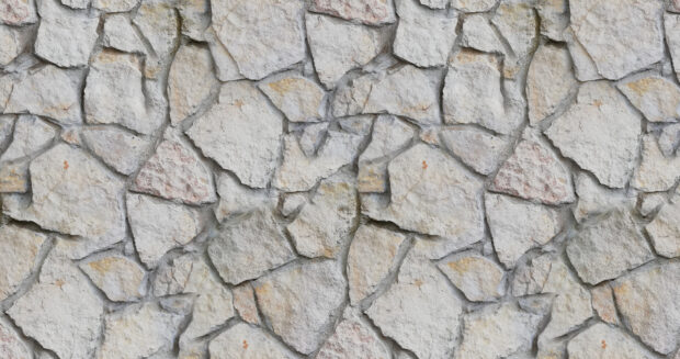 Rough stone wall with natural texture and uneven shapes forming a rustic stone pattern