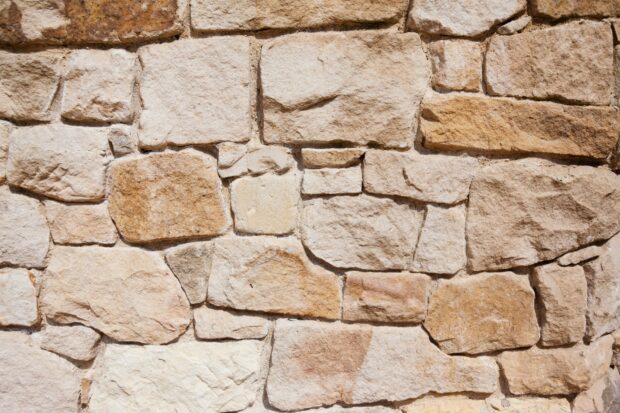 Close up of natural stone wall showing rough texture and variety of shapes