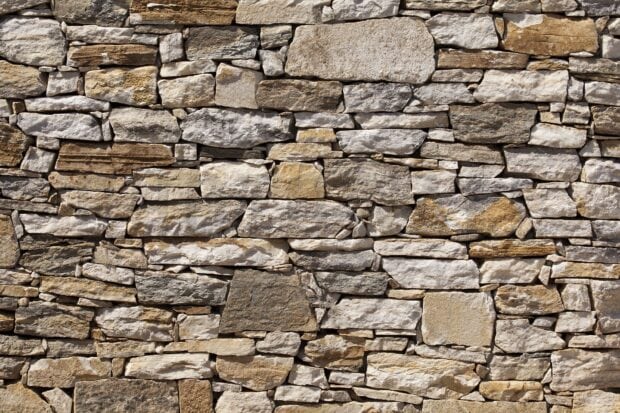 A rustic stone wall with various shaped stones forming a natural pattern