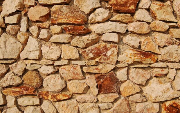 Natural stone wall with rough textured surfaces in earthy colors