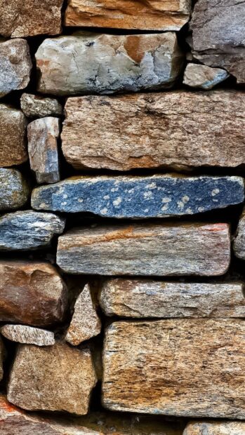 Close up of natural stone wall texture with rough surfaces and various colors