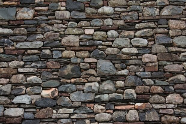 A close up view of various natural stone arranged in a rustic pattern on a wall