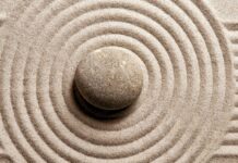 A single stone surrounded by concentric circles in fine sand forming a Zen stone pattern
