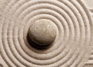 A single stone surrounded by concentric circles in fine sand forming a Zen stone pattern