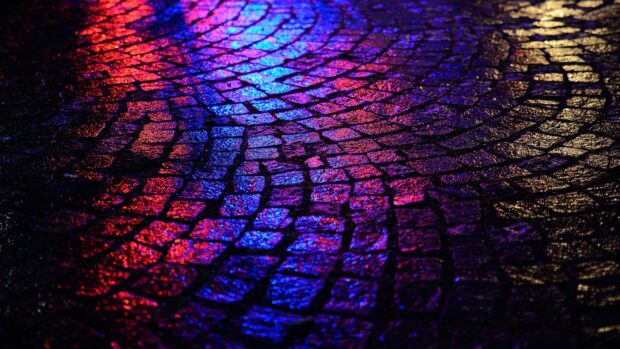 Colorful light reflecting on wet stone pavement at night