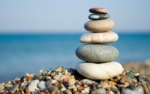 A stack of smooth stone balanced on a pebble beach near the sea