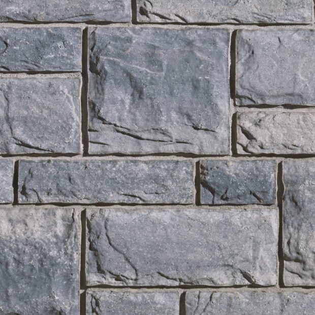 Close up of textured stone wall with gray rough stones and mortar joints
