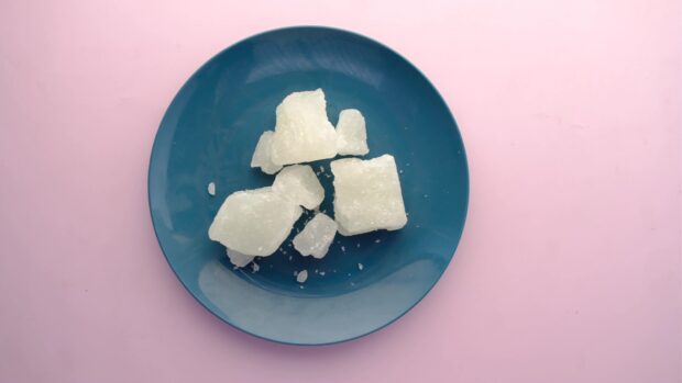 White sugar crystals on a blue plate on a pink surface