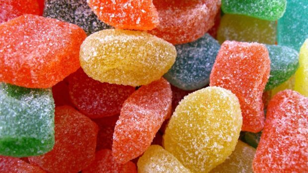 Colorful sugar candy pieces covered with granulated sugar crystals close up view