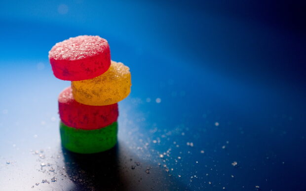 Colorful sugar stacked on blue surface with sugar crystals scattered around