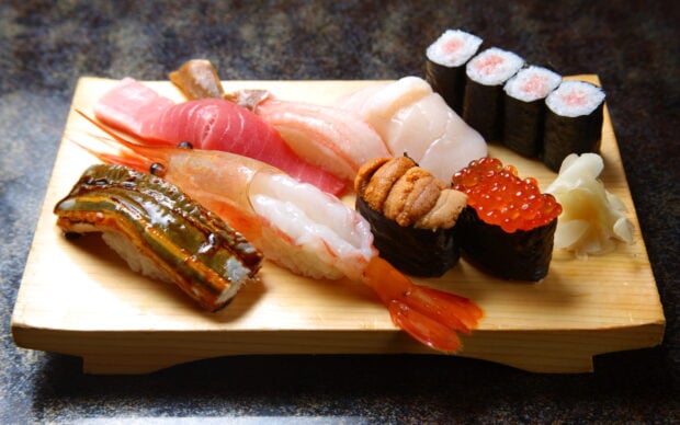 A variety of sushi including shrimp and roe served on a wooden platter rich in sushi ingredients