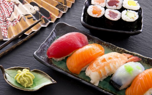 A sushi assortment with tuna salmon shrimp and squid pieces on a ceramic plate