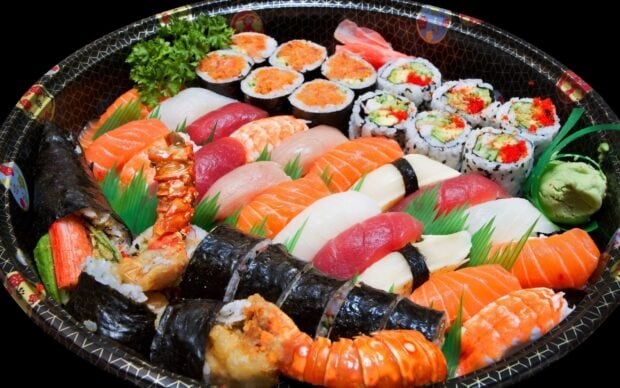A variety of sushi rolls and nigiri with fresh seafood and vegetables displayed in a tray