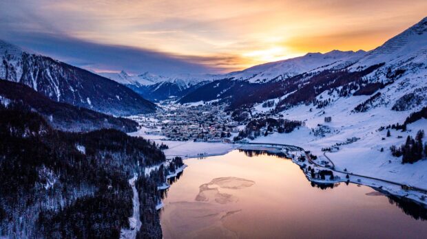 Aerial view of a Switzerland town surrounded by snowy mountains and a lake at sunset