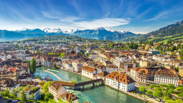 Scenic Switzerland cityscape with river bridge and mountains in the background